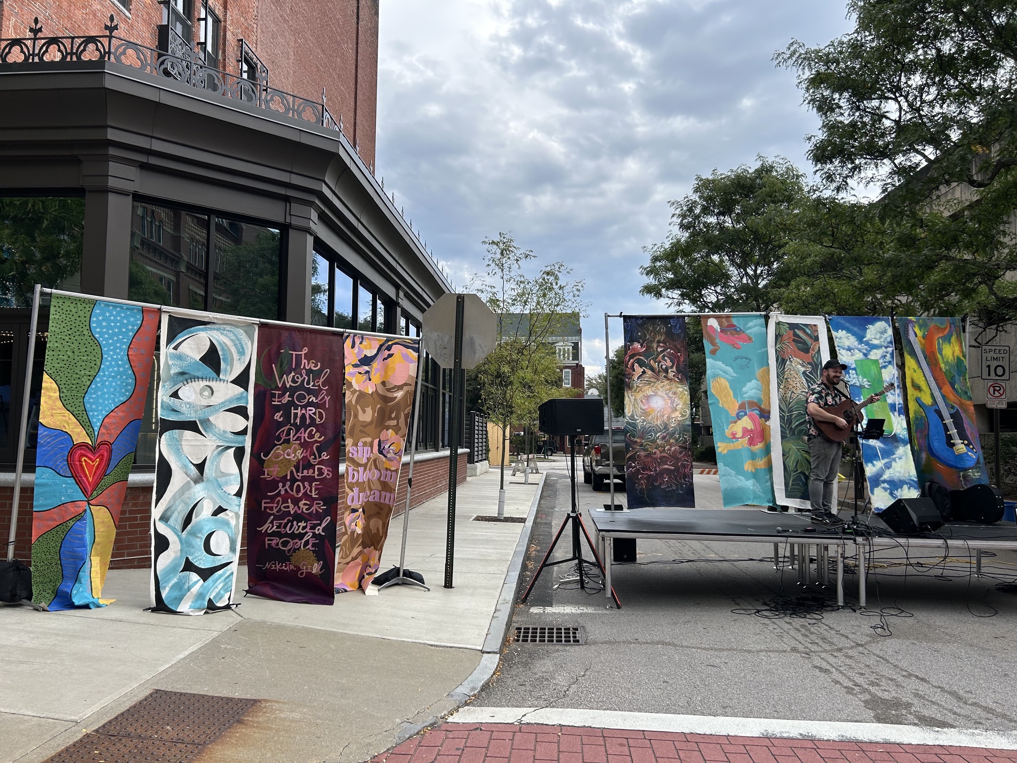 An outdoor public art display with mural panels and visitors gathered around